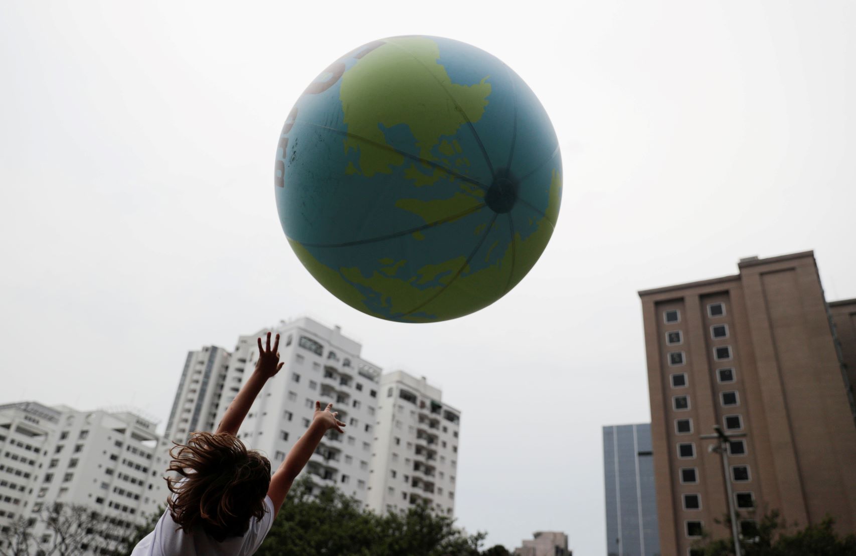 A girl plays with a ball decorated as globe in front of buildings during the Global Climate Strike of the Fridays for Future movement in Sao Paulo, Brazil on September 20, 2019. 