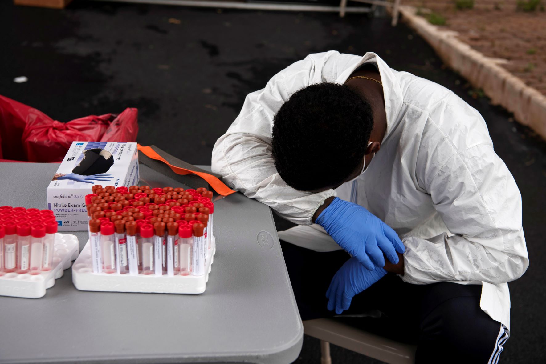 Overheated, a healthcare worker takes a break as people wait in their vehicles in long lines for the COVID-19 testing in Houston, Texas on July 7, 2020. REUTERS/Callaghan O'Hare